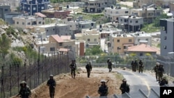 With the Druze village of Majdal Shams in the background, Israeli troops patrol along the border between Israel and Syria the Golan Heights, May 20, 2011