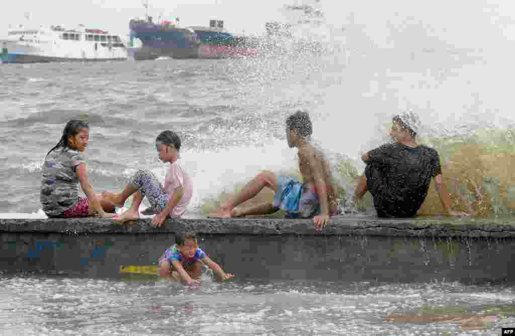 Residents along Manila Bay play in the waves created by nearby Typhoon Noul as it approaches the northern Philippines.