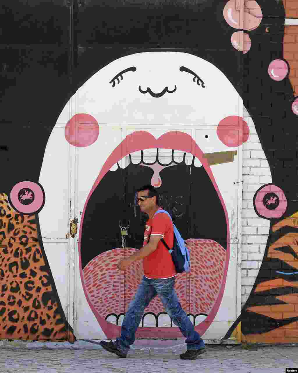 A man walks past graffiti on a wall in Lisbon.