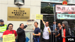 集會人士把遊行宣言抗議信貼到香港中聯辦銅牌的旁邊（美國之音譚嘉琪）