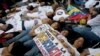 FILE - Opposition supporters lie on the ground during a demonstration outside of the Organization of American States, OAS, office building, in Caracas, Venezuela, June 23, 2016.