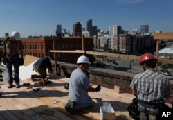 A construction team works on the roof of a high-end office building in Denver, Colorado. The city has one of the nation's fastest-growing economies, with high demand for new housing and office space.