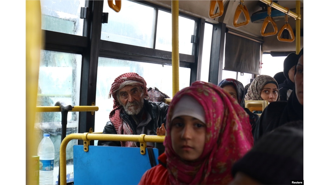 FILE - Evacuees from the Shi'ite Muslim villages of al-Foua and Kefraya ride a bus at insurgent-held al-Rashideen in the province of Aleppo, Dec. 22, 2016.