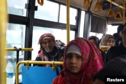 FILE - Evacuees from the Shi'ite Muslim villages of al-Foua and Kefraya ride a bus at insurgent-held al-Rashideen in the province of Aleppo, Dec. 22, 2016.