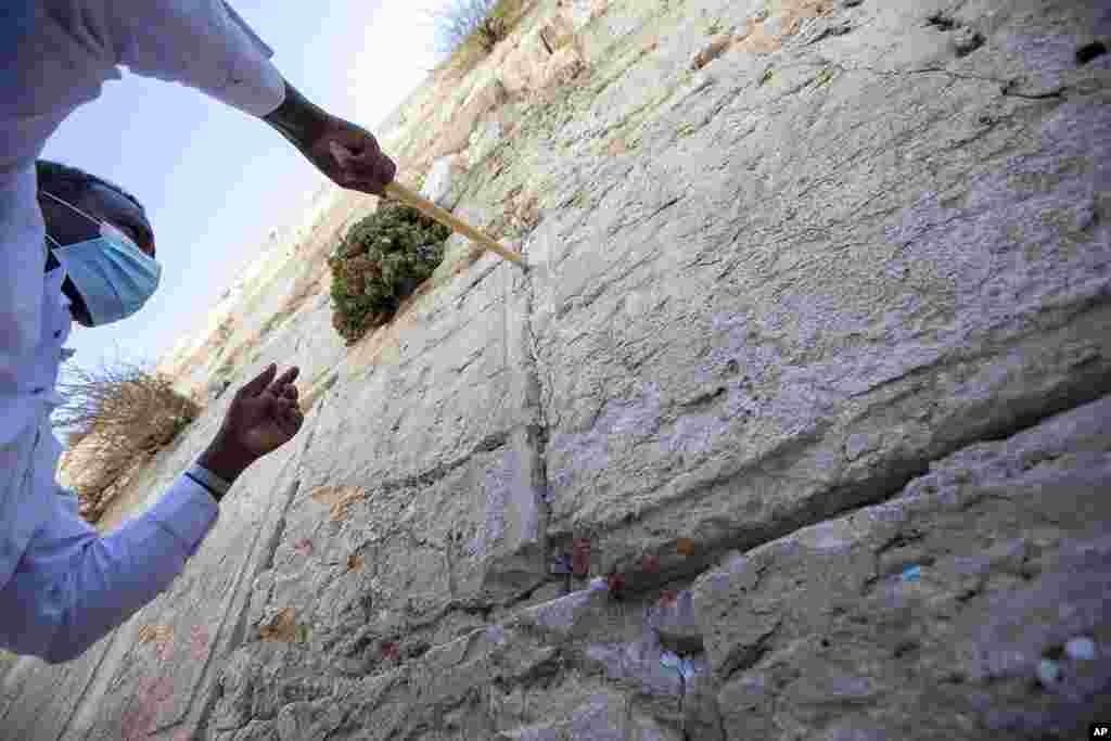 A worker removes prayer notes left by visitors between stones at the Western Wall, the holiest site where Jews can pray in Jerusalem&#39;s old city, ahead of Rosh Hashana, the Jewish new year. The notes are buried in a nearby cemetery.