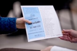 Una mujer toma una hoja de votación demócrata para votar en la primarias de New Hampshire en la escuela Parker-Varney Elementary, el martes 11 de febrero de 2020 en Manchester, N.H.