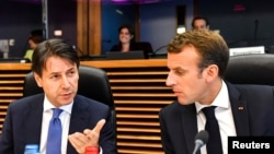 French President Emmanuel Macron, right, speaks with Italian Prime Minister Giuseppe Conte during a round table meeting at an informal EU summit on migration at EU headquarters in Brussels, June 24, 2018.