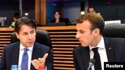 Presiden Perancis Emmanuel Macron (kanan) berbicara dengan Perdana Menteri Italia Giuseppe Conte dalam pertemuan meja bundar di KTT Uni Eropa untuk masalah migrasi di markas besar Uni Eropa, Brussels, Belgia, 24 Juni 2018.
