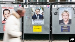 A man walks past electoral posters displaying the presidential candidates, Benoit Hamon, left, Emmanuel Macron, center, and Marine Le Pen in Paris, France, April 17, 2017. 