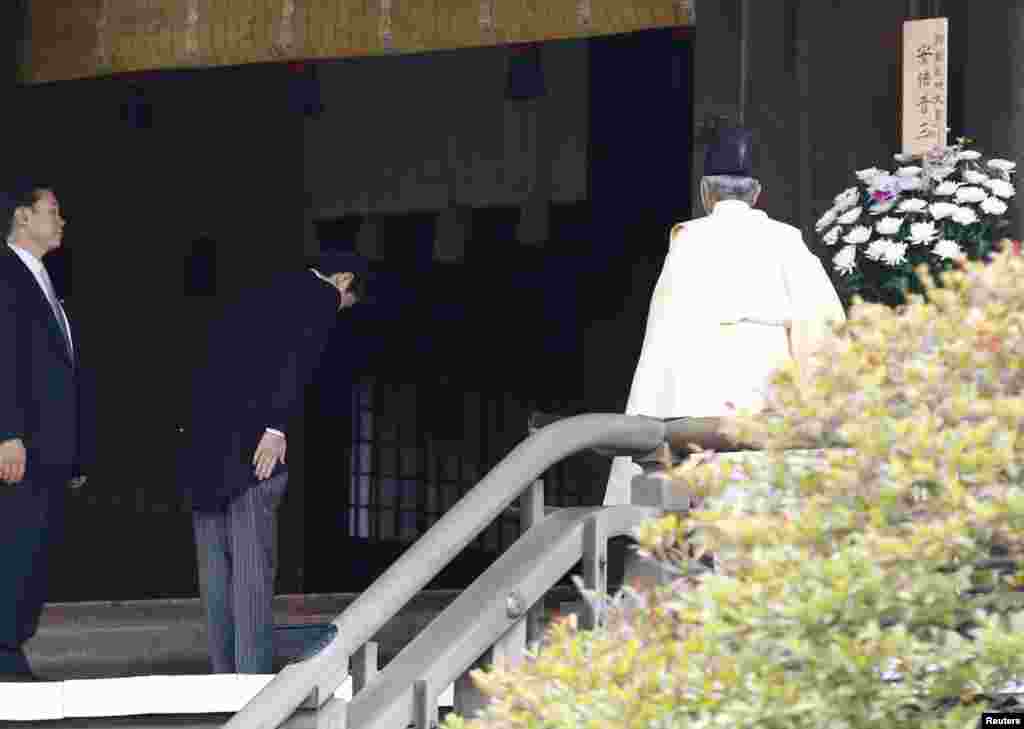 Japan&#39;s Prime Minister Shinzo Abe bows beside a Shinto priest as he visits Yasukuni Shrine in Tokyo, Dec. 26, 2013. 