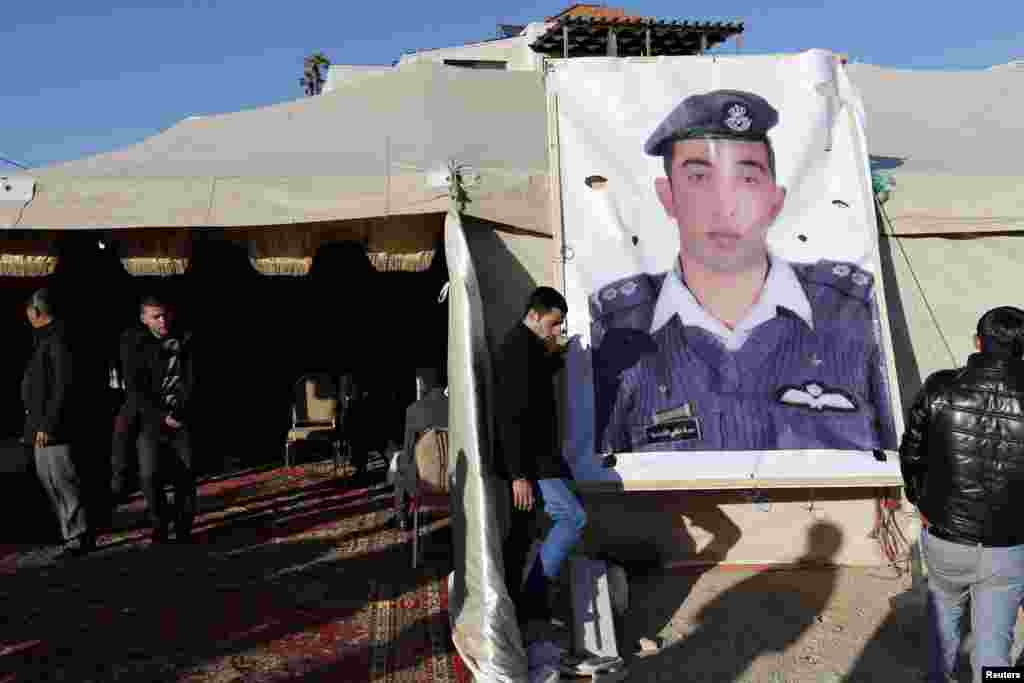 Relatives of Islamic State captive Jordanian pilot Muath al-Kasaesbeh place a poster of him in front of their new gathering headquarters in Amman. Japan and Jordan scrambled on Friday to find out what had happened to two of their nationals being held by IS, after a deadline passed for the release of a would-be suicide bomber being held on death row in Amman. 