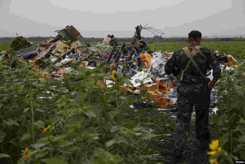 A pro-Russian separatist looks at wreckage from the nose section of a Malaysia Airlines Boeing 777 plane which was downed near the village of Rozsypne, in the Donetsk region, July 18, 2014.