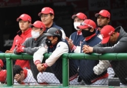 SK Wyverns players wearing face masks watch the game from the dugout during the opening game against Hanwha Eagles for South Korea's new baseball season at Munhak Baseball Stadium in Incheon on May 5, 2020.