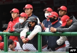 SK Wyverns players wearing face masks watch the game from the dugout during the opening game against Hanwha Eagles for South Korea's new baseball season at Munhak Baseball Stadium in Incheon on May 5, 2020.