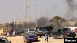 Protesters run after an attack on a Libyan militia, the Libya Shield brigade, headquarters in Benghazi, Jun. 8, 2013.