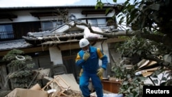 Un policier contrôle une maison submergée et détruite dans une zone touchée par les inondations dans la ville de Mabi à Kurashiki, préfecture d'Okayama, Japon, 10 juillet 2018.