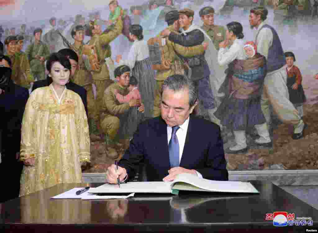 朝鲜中央通讯社2018年5月3日发布的这张照片中，中国国务委员兼外长王毅在访问平壤期间签名或者题词，后面的画作题材似乎是1950年代所谓中国志愿军在朝鲜。