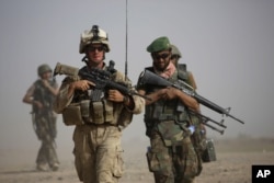 FILE - A U.S. Marine and an Afghan soldier are seen on joint patrol in Helmand province, southern Afghanistan, Oct. 3, 2009.