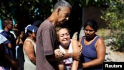 Relatives react as police investigators work at a crime scene where five men were killed in El Salvador on Jan. 1, 2016.