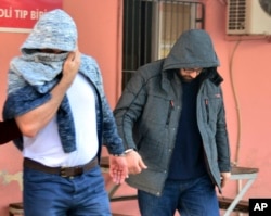 Two men, identified by Turkey's state-run news agency, as Mahamad Laban, 45, right, and Mohammed Tofik Saleh, 38, walk to a police van outside a police station in Adana, Turkey, Feb. 11, 2017. The Anadolu news agency said that the arrested men were suspected of receiving Islamic State group weapons and explosives training in Syria for the past three months and of planning attacks in Europe.