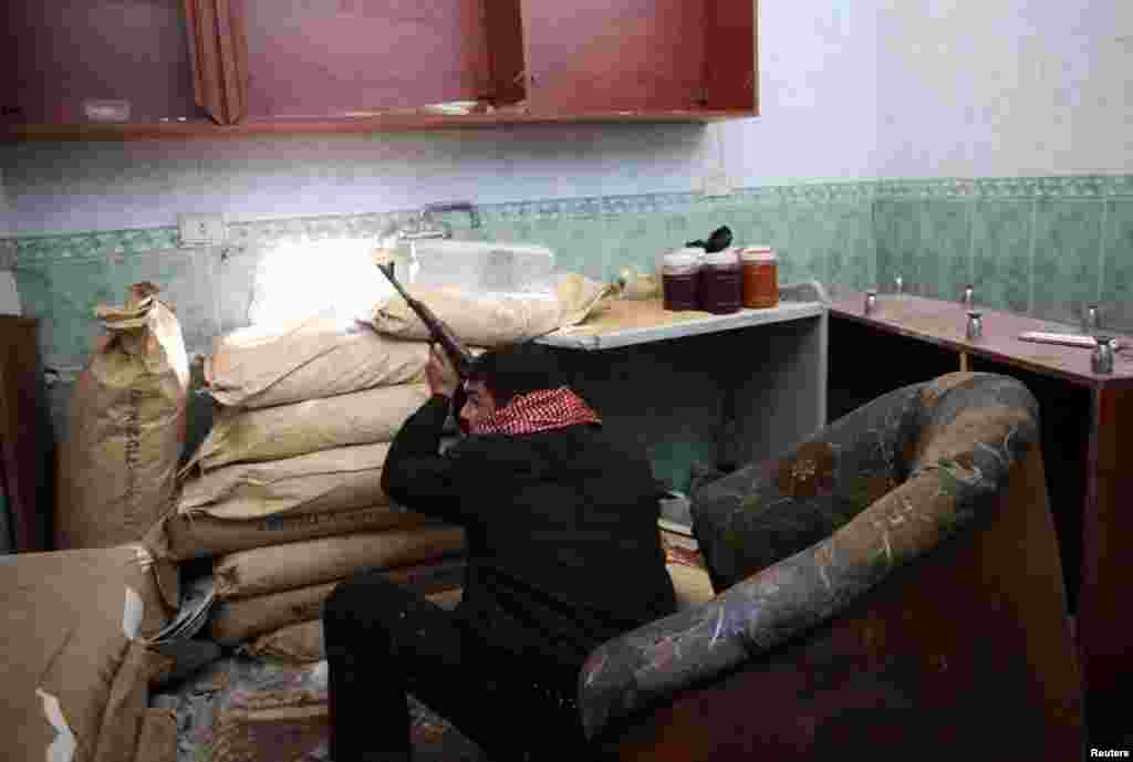 A Free Syrian Army fighter takes position inside a house during clashes with forces loyal to Syria's President Bashar al-Assad in Damascus, February 12, 2013.