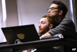 Sam Alexander holds his son, Ben, during a class for screenwriting at Tulane University in New Orleans. In his classes, Ben, who has nonverbal autism, sits with his dad at his side. Photo taken March 2, 2016. (AP photo)