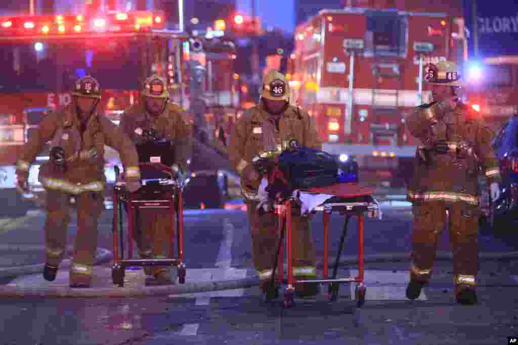 Los Angeles Fire Department firefighters push ambulance stretchers at the scene of a structure fire that injured multiple firefighters, according to a fire department spokesman, May 16, 2020, in Los Angeles, California.