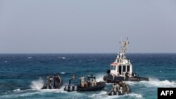 Para penjaga pantai Libya menunggu kedatangan kapal tanker Morning Glory (22/3) di pelabuhan Zawiya, Libya.