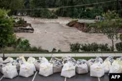 Floodwaters rush through the breach of the Columbia Canal as emergency workers prepare giant sandbags to plug the hole in Columbia, S.C., Oct. 5, 2015.