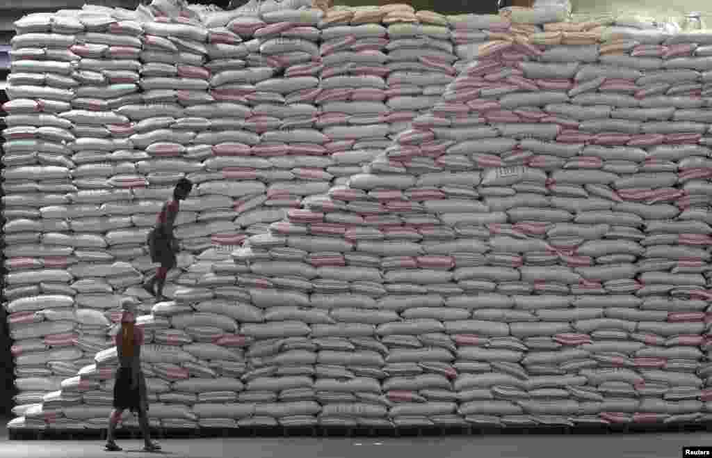 A worker walks up a pile of sacks of rice at a warehouse of the Philippines National Food Authority in Manila.