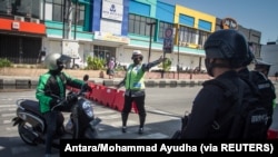 Petugas kepolisian menghentikan sepeda motor akibat pemberlakuan PPKM di Jawa dan Bali di tengah lonjakan kasus COVID-19, di Solo, Jawa Tengah, 8 Juli 2021. (Foto: Antara/Mohammad Ayudha via REUTERS)