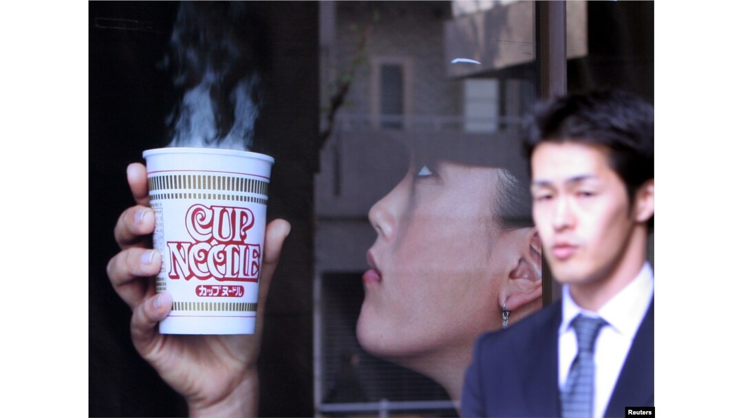 Seorang pria melewati iklan pembuat mie instan terkemuka Jepang Nissin Food Products dengan pemain golf bintang Michelle Wie memegang "Cup Noodle", di kantor pusat perusahaan di Tokyo. (REUTERS/Toshiyuk Aizawa)