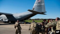 This Oct. 29, 2018 photo provided by the U.S. Air Force shows deployers from Headquarters Company, 89th Military Police Brigade, Task Force Griffin getting ready to board a C-130J Super Hercules from Little Rock, Arkansas, at Fort Knox, Kentucky.