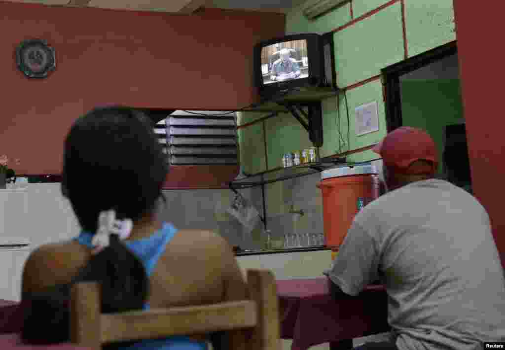 People in a restaurant watch Cuban president Raul Castro speaking during a state television broadcast in Havana, Cuba, Dec. 17, 2014.