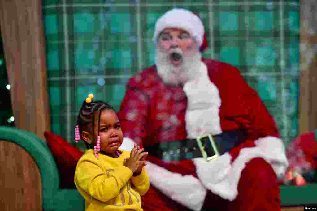 Majesty Davis, 3, cries during a visit to Santa Claus, who sits behind a plexiglass divider due to the COVID-19 pandemic, at the Willow Grove Park Mall in Willow Grove, Pennsylvania, Nov. 14, 2020.