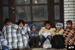 FILE - Children sit under covers as they wait with migrants and refugees near the registration camp in the town of Presevo after their arrival in Serbia in September 2015.