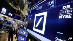 Traders walk by the post where Deutsche Bank is traded on the floor of the New York Stock Exchange, Monday, Sept. 26, 2016.