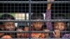 Cambodian migrants look through grills of a truck as they wait to cross the Thai-Cambodia border at Aranyaprathet in Sa Kaew June 15, 2014