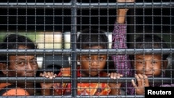 柬埔寨难民在卡车里向外张望，等待跨越泰国-柬埔寨边界（2014年6月15日）。联合国秘书长古特雷斯说：“人们一旦开始流动，坏人就有了可乘之机。” 难民营成了人口贩子寻找猎物的丰富猎场。”