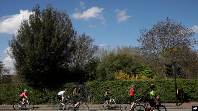 Ciclistas observan el distanciamiento social mientras esperan en un semáforo en Regent's Park, Londres, el sábado 4 de abril de 2020.