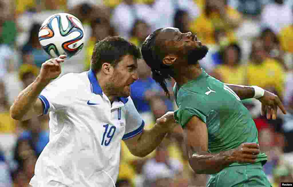 Greece's Sokratis Papastathopoulos, left, fights for the ball with Ivory Coast's Didier Drogba during their match at the Castelao arena in Fortaleza ,June 24, 2014.