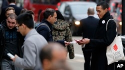 FILE - A pro-Brexit campaigner hands out leaflets at Liverpool Street station in London, March 23, 2016. EU officials warn that Britain would be the bigger loser should it decide to leave the bloc.