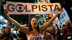 Seorang demonstran memegang spanduk bertuliskan "Pemimpin kudeta" dalam bahasa Portugis, dalam demonstrasi melawan penjabat presiden Michael Temer dan mendukung Presiden Dilma Rousseff di Rio de Janeiro, Brazil (29/8). (AP/Silvia Izquierdo)