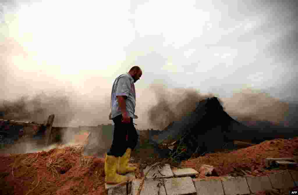 June 6: A Libyan fireman looks at the damage of a shoe warehouse which was hit by Grad rockets fired by forces loyal to Muammar Gaddafi at Misrata's western front line. REUTERS/Zohra Bensemra