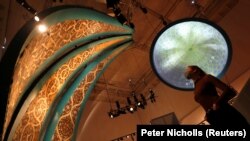 Seorang pegawai museum V&A melihat Dome Prejection dan lukisan-lukisan segitiga yang menggambarkan interior kubah masjid dalam pameran Epic Iran yang akan segera dibuka di London, Inggris, 25 Mei 2021. (Foto: Peter Nicholls/Reuters)