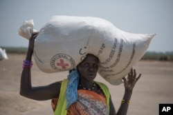 FILE - In this photo taken April 11, 2017, a woman walks back to her home after receiving food distributed by the Red Cross in South Sudan.