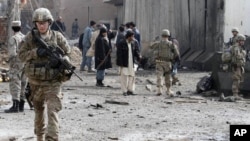 U.S. soldiers and Afghan policemen keep watch after a car bomb blast in the southern city of Kandahar, Afghanistan, February 20, 2012.