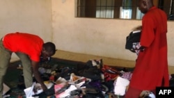 A student aided by a porter rummages through personal effects abandoned by students at the Federal College of Education in the northern Nigerian city of Kano, Sept. 17, 2014, following an attack by gunmen who stormed the lecture hall opening fire on students.