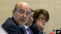 French Foreign Minister Alain Juppe (L) and Syrian Auditing Consultant Maria Chatti attend an international conference of a working group monitoring sanctions against the Syrian regime in Paris, April 17, 2012