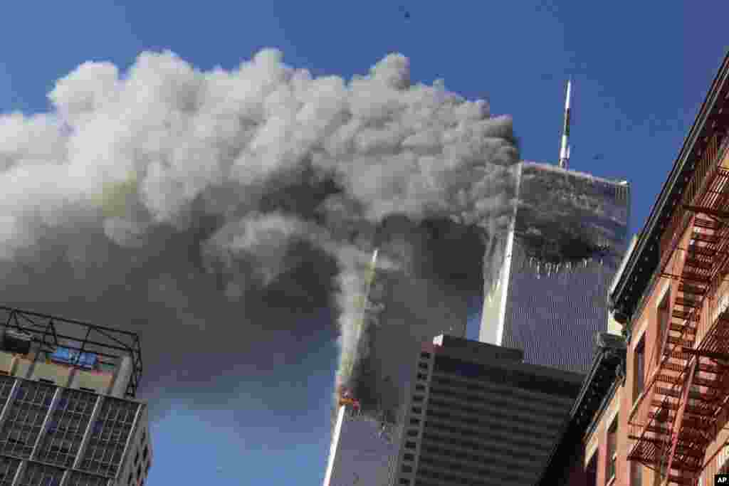 FILE - In this Sept. 11, 2001, file photo, smoke rises from the burning twin towers of the World Trade Center after hijacked planes crashed into the towers, in New York City. The coronavirus pandemic has reshaped how the U.S. is observing the anniversary of 9/11. The terror attacks&#39; 19th anniversary will be marked Friday, Sept. 11, 2020, by dueling ceremonies at the Sept. 11 memorial plaza and a corner nearby in New York. (AP Photo/Richard Drew, File)